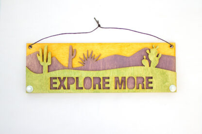 layered desert wooden sign, reads "Explore More," in green