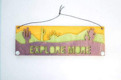 layered desert wooden sign, reads "Explore More," in purple