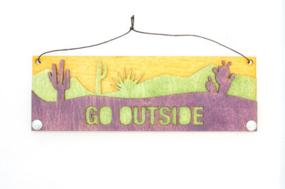 Desert text sign with text "go outside," in purple