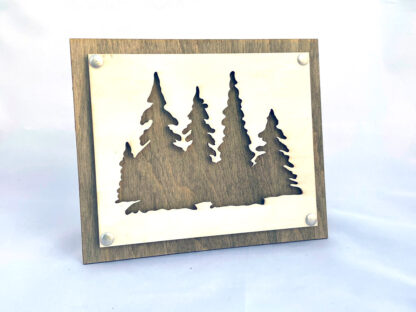 Two-layered wooden wall art depicting a scene of evergreen trees in the lush forests of the mountains